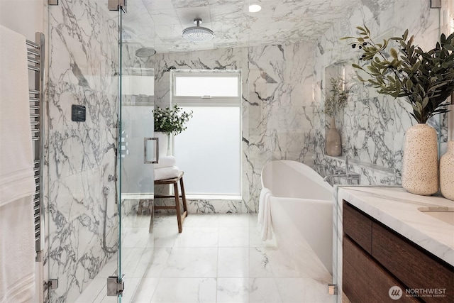 full bath featuring vanity, a marble finish shower, marble finish floor, a freestanding tub, and tile walls