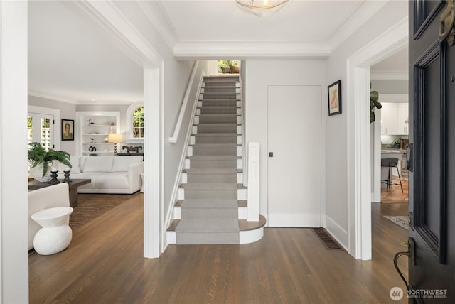 foyer entrance featuring crown molding, visible vents, stairs, wood finished floors, and baseboards