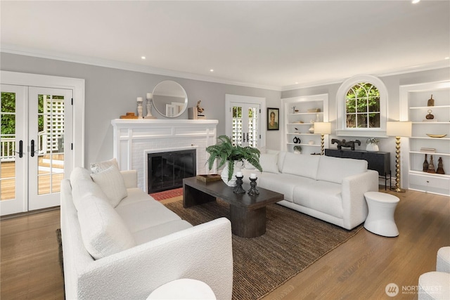 living room featuring built in shelves, ornamental molding, french doors, and wood finished floors