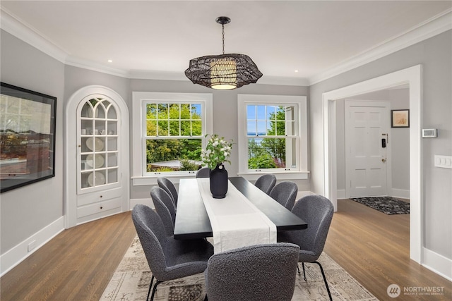 dining area with baseboards, ornamental molding, and wood finished floors
