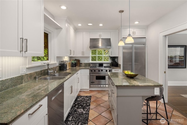 kitchen featuring a breakfast bar area, a sink, under cabinet range hood, stainless steel appliances, and white cabinetry