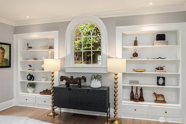 living area featuring baseboards, ornamental molding, and wood finished floors