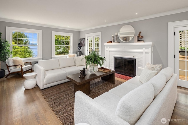 living room featuring a brick fireplace, ornamental molding, and wood finished floors