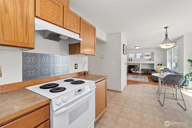 926 99th St SW, Everett, WA 98204 - kitchen with white electric range oven, under cabinet range hood, a warm lit fireplace, pendant lighting, and open floor plan