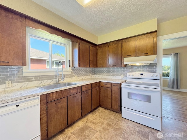 kitchen with under cabinet range hood, white appliances, a sink, and light countertops