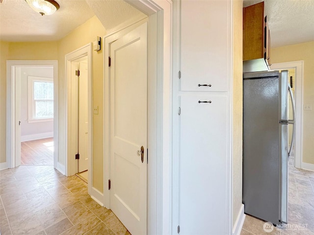 corridor with a textured ceiling and baseboards