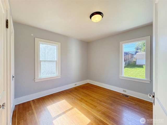 spare room featuring visible vents, wood finished floors, and baseboards