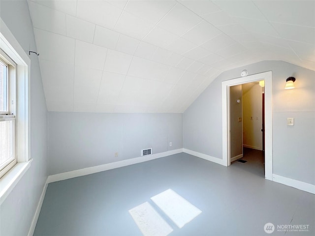 additional living space with lofted ceiling, baseboards, and visible vents