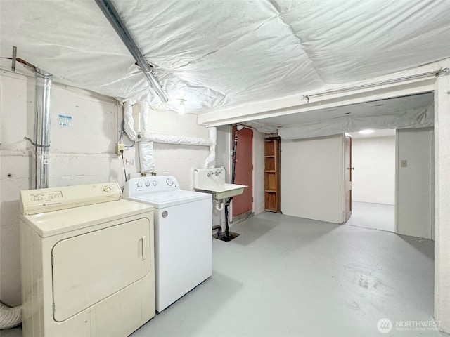 clothes washing area featuring washer and clothes dryer, laundry area, and a sink