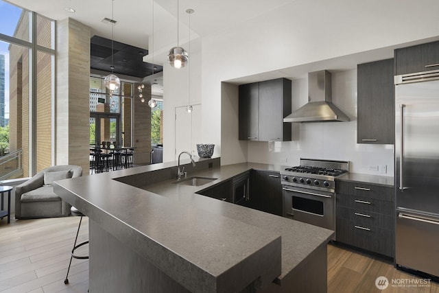 10610 NE 9th Pl Unit G403, Bellevue, WA 98004 - kitchen with wall chimney range hood, premium appliances, a sink, modern cabinets, and wood finished floors