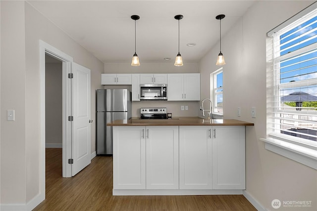 3315 N 35th St, Tacoma, WA 98407 - kitchen with pendant lighting, appliances with stainless steel finishes, wood finished floors, baseboards, and a peninsula