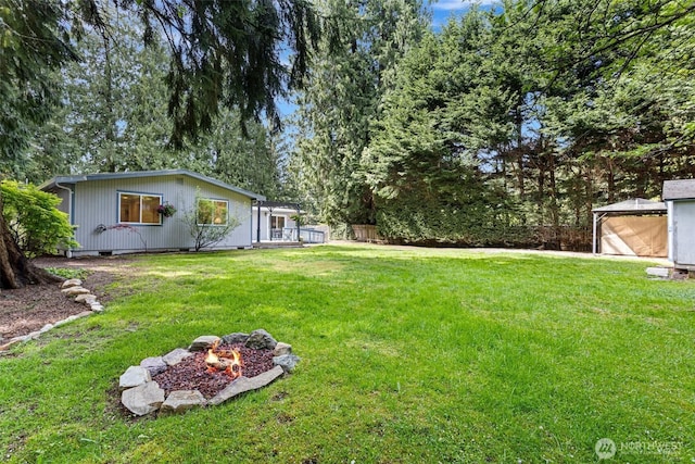 view of yard with a fire pit and an outbuilding