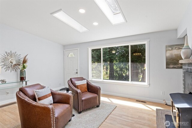 sitting room with a skylight, baseboards, recessed lighting, and wood finished floors