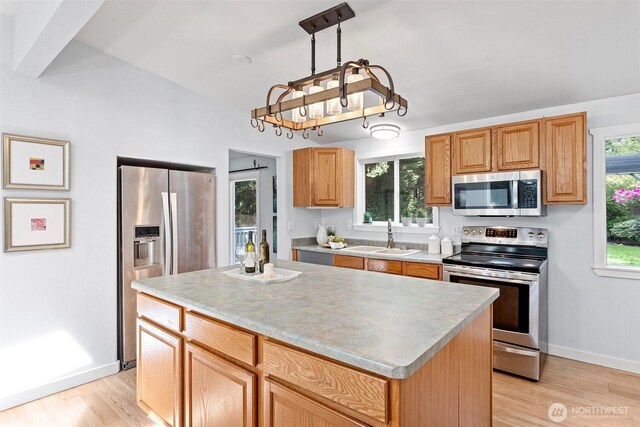 kitchen with stainless steel appliances, baseboards, a sink, and light wood-style flooring