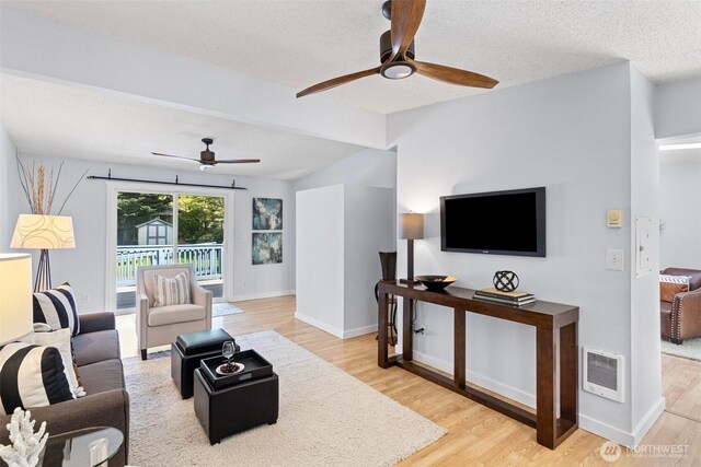 living area with a textured ceiling, ceiling fan, wood finished floors, and visible vents
