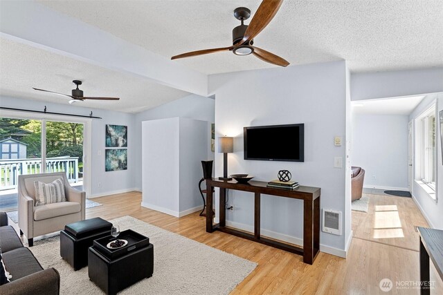 living area with a textured ceiling, ceiling fan, visible vents, and wood finished floors