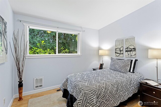 bedroom featuring baseboards, wood finished floors, and visible vents