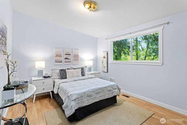 bedroom featuring baseboards, visible vents, and wood finished floors