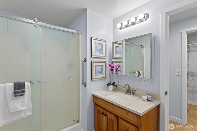 bathroom with vanity, a stall shower, and wood finished floors