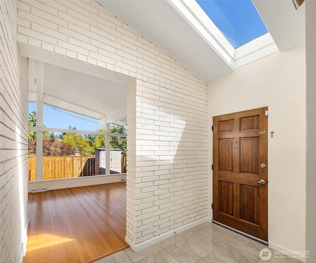 9750 SE 41st St, Mercer Island, WA 98040 - entrance foyer with brick wall, visible vents, wood finished floors, and vaulted ceiling with skylight