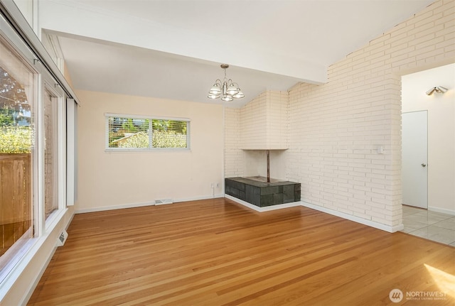 9750 SE 41st St, Mercer Island, WA 98040 - unfurnished living room featuring brick wall, visible vents, vaulted ceiling, light wood finished floors, and an inviting chandelier
