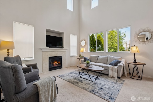 carpeted living room featuring baseboards, a high ceiling, and a fireplace