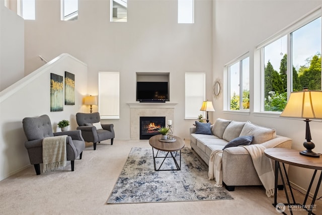 carpeted living area featuring a tile fireplace and a towering ceiling