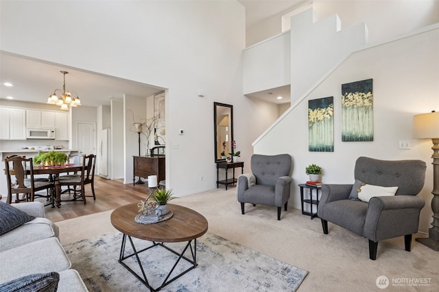 living area featuring a high ceiling, an inviting chandelier, light carpet, recessed lighting, and baseboards