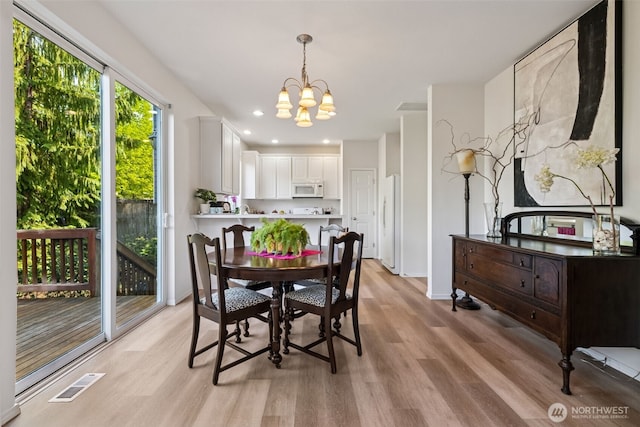 dining area with baseboards, a notable chandelier, light wood finished floors, and visible vents