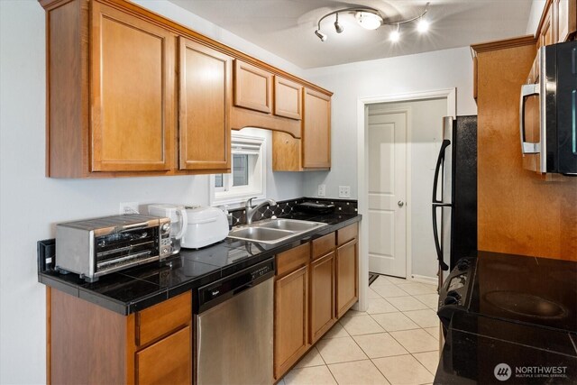 kitchen featuring brown cabinetry, a sink, appliances with stainless steel finishes, and light tile patterned flooring