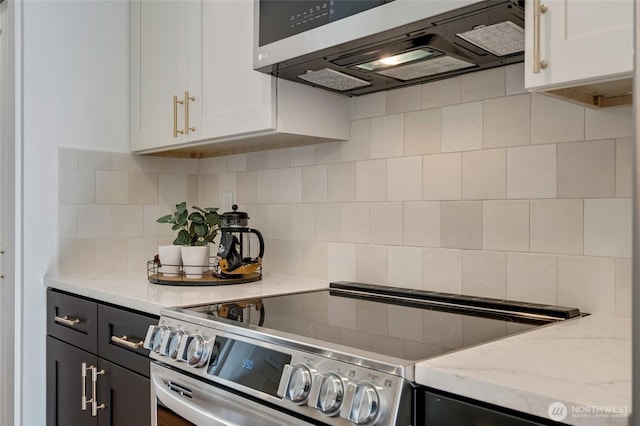 321 Bellevue Way SE Unit 401, Bellevue, WA 98004 - kitchen with decorative backsplash, light stone counters, white cabinetry, extractor fan, and appliances with stainless steel finishes