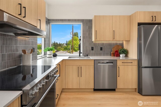 3650 51st Ave SW Unit B, Seattle, WA 98116 - kitchen with appliances with stainless steel finishes, light brown cabinets, a sink, backsplash, and light wood-style flooring