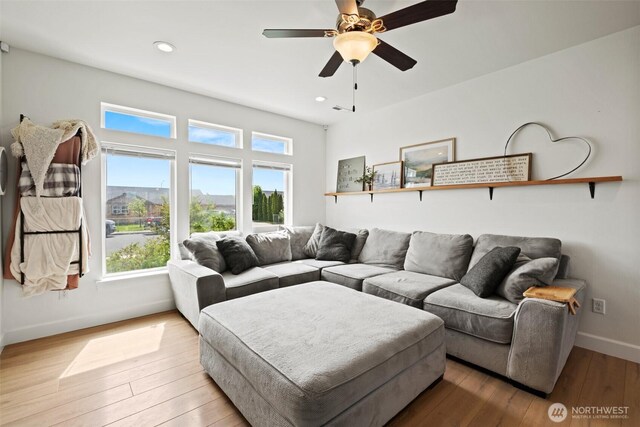 living area featuring baseboards, recessed lighting, light wood finished floors, and a wealth of natural light