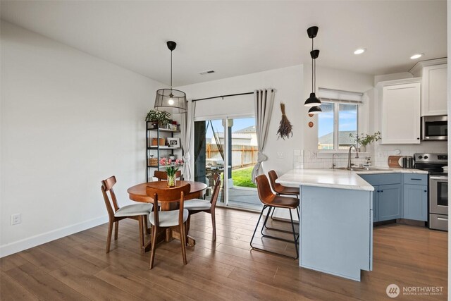 kitchen featuring a kitchen breakfast bar, light countertops, white cabinets, tasteful backsplash, and stainless steel appliances