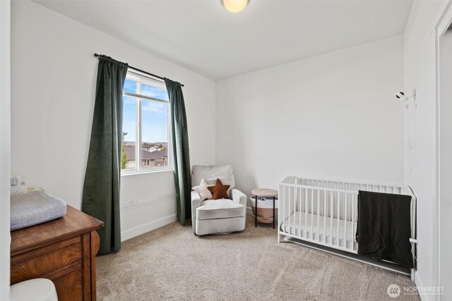 carpeted bedroom featuring baseboards and a nursery area