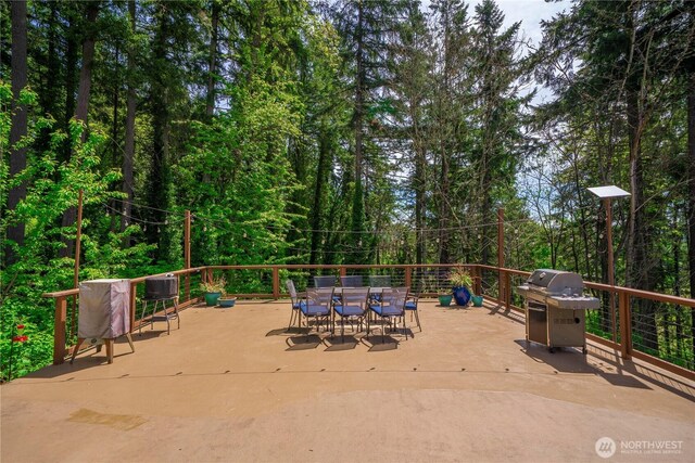 view of patio / terrace with grilling area, outdoor dining area, and a forest view