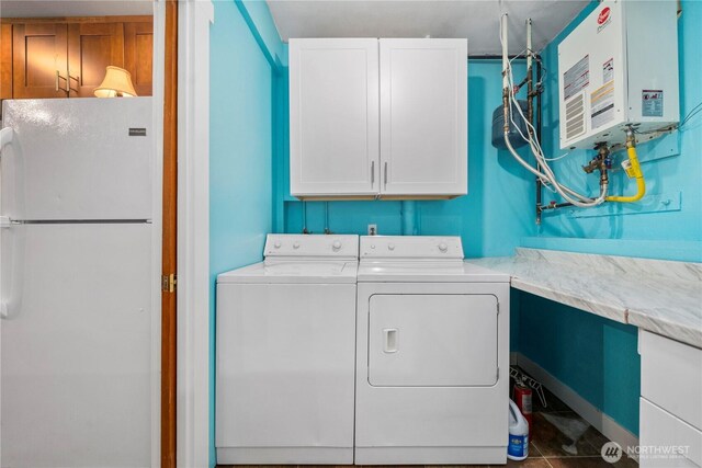 laundry area featuring washing machine and dryer, cabinet space, water heater, and tile patterned flooring