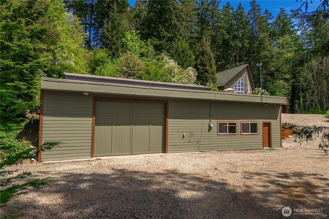 garage with driveway and a forest view