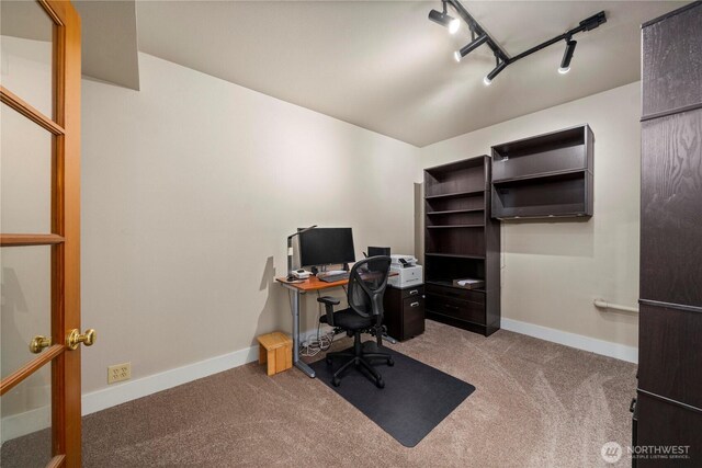 carpeted office featuring rail lighting and baseboards