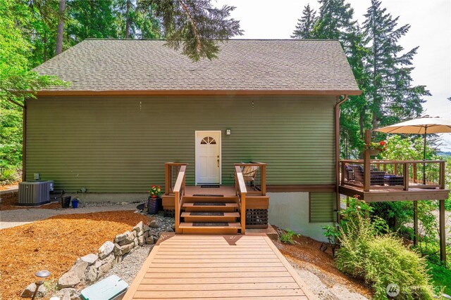 back of house featuring a wooden deck, central air condition unit, and roof with shingles