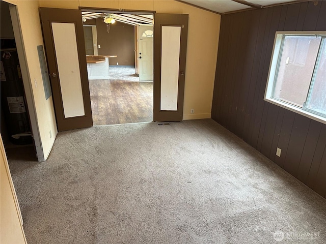 10206 218th Ave E, Bonney Lake, WA 98391 - carpeted spare room featuring visible vents, wood walls, and ceiling fan