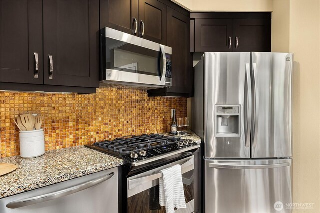 kitchen with appliances with stainless steel finishes, light stone countertops, backsplash, and dark brown cabinetry