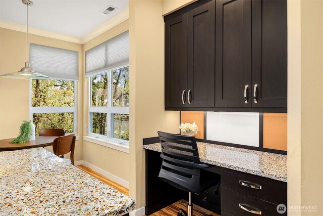 office space featuring visible vents, crown molding, built in study area, baseboards, and light wood-style flooring