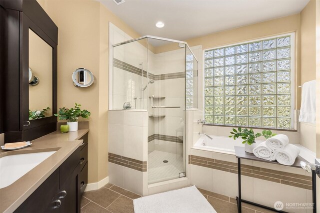 full bathroom with a healthy amount of sunlight, tile patterned floors, a shower stall, and a garden tub