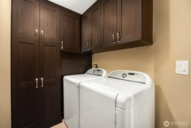 clothes washing area with cabinet space and washer and dryer