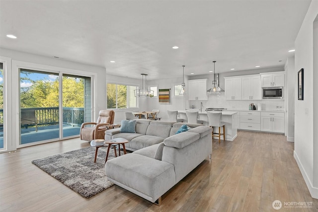 living area with recessed lighting, baseboards, a chandelier, and light wood-type flooring