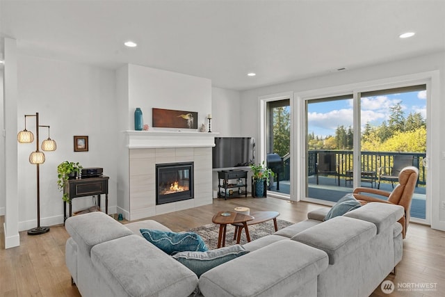 living area featuring recessed lighting, wood finished floors, and a tile fireplace