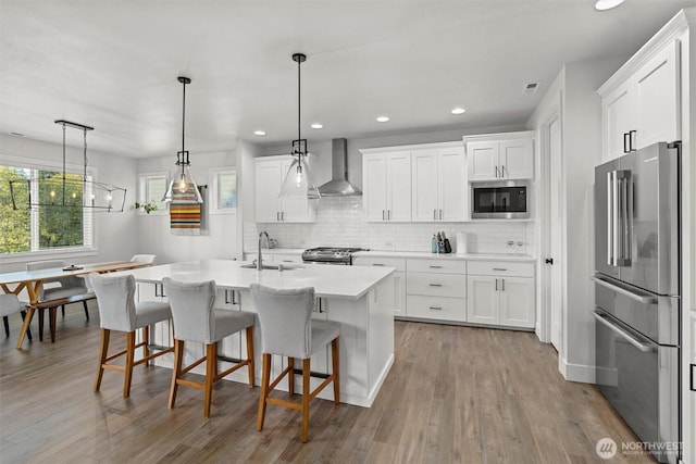 kitchen featuring wall chimney range hood, appliances with stainless steel finishes, tasteful backsplash, and a sink
