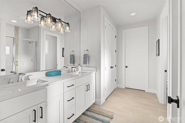full bath with double vanity, a sink, baseboards, and a shower stall