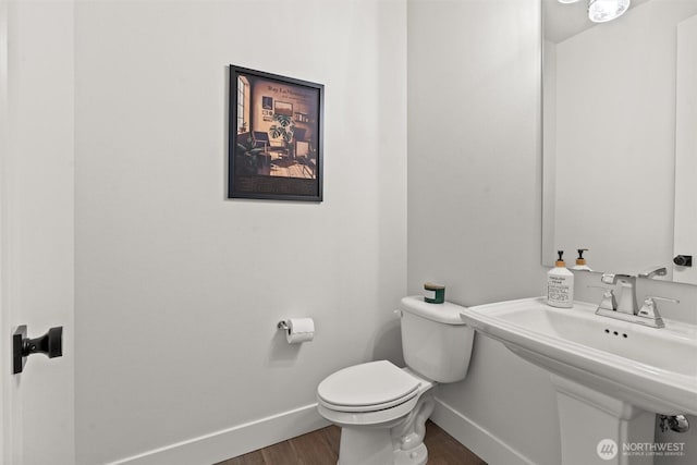 bathroom featuring baseboards, a sink, wood finished floors, and toilet